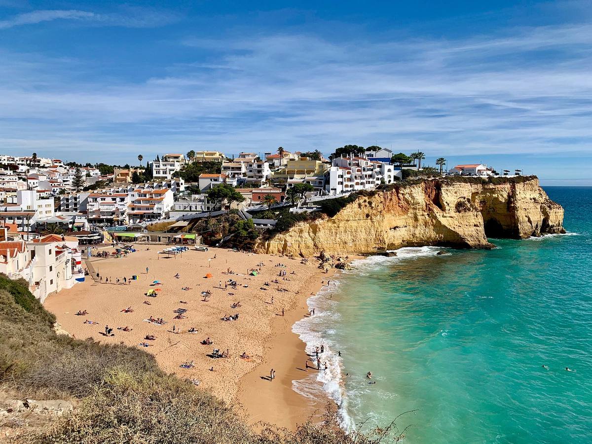 Le village blanc de Carvoeiro en cascade au-dessus de sa plage en croissant, entre les falaises ocre