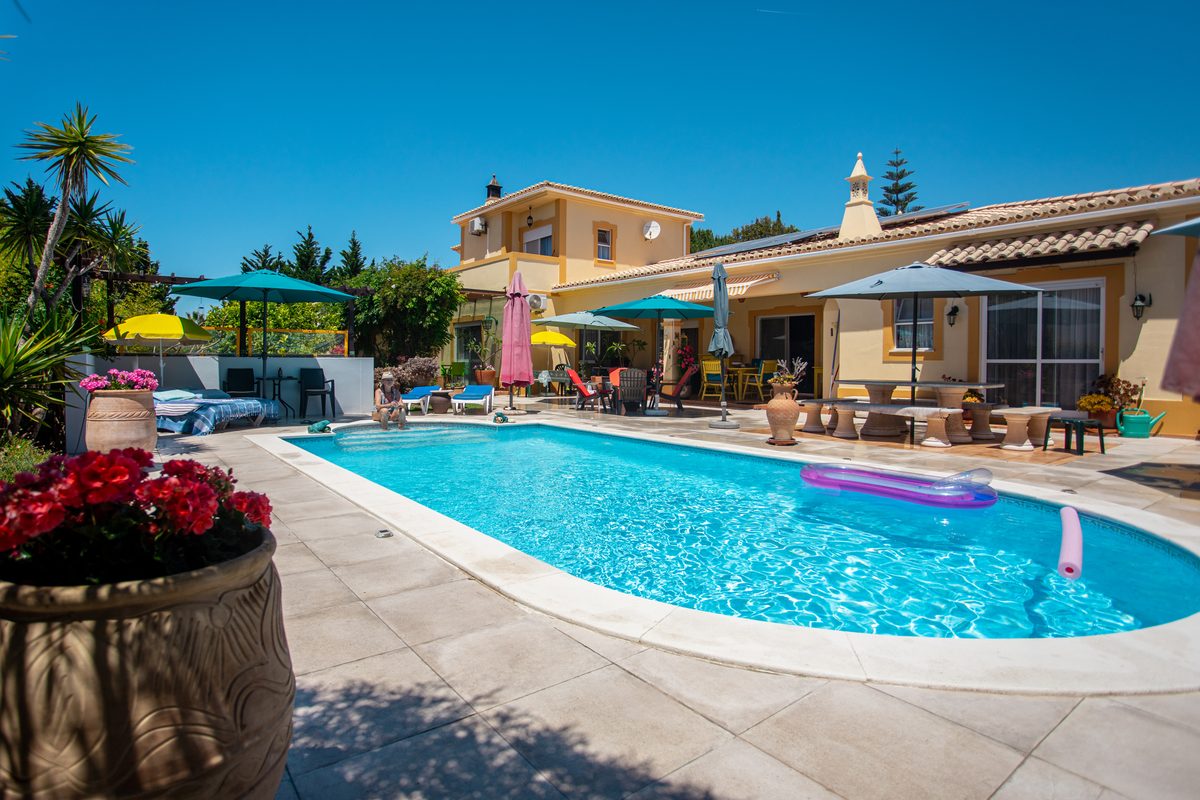 Le Studio vu depuis la piscine : sa porte-fenêtre, la terrasse et la grande table en pierre
